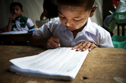 A young Burmese boy learns to write in a kindergarten class. Photo by UN Photo on flickr.