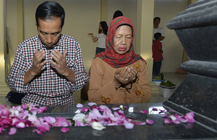 Presidential candidate Joko Widodo and his mother pray at his father's tomb. Photo by AFP.