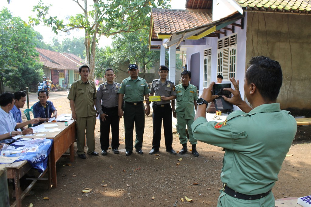 The village secretary (left) tours the polling stations with TNI (centre), police (centre right) and the village security (far right). 