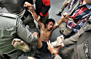 An injured resident of Kampung Pulo is dragged away by police. Photo: Antara.