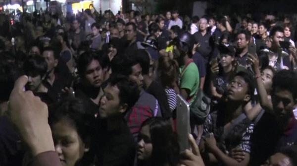 A mob gathers outside Mr Suthee's shop in Phuket.