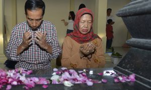 Indonesian presidential candidate Joko Widodo and his mother pray at his father's tomb. Photo by AFP.