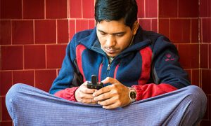 A young Burmese man checks his mobile phone. Photo by thaths on flickr.