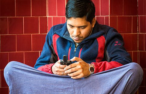 A young Burmese man checks his mobile phone. Photo by thaths on flickr.