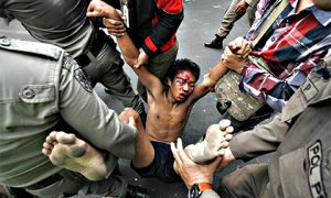 An injured resident of Kampung Pulo is dragged away by police. Photo: Antara.